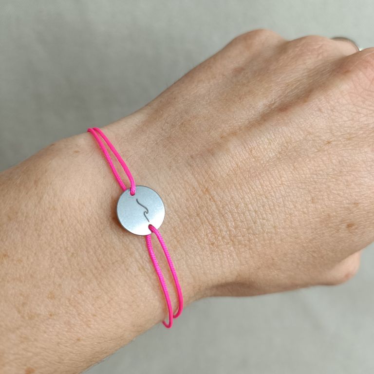 Armband mit pinkem Band und Edelstahlplättchen, graviert mit einer Welle – handgefertigt und individuell gestaltet.